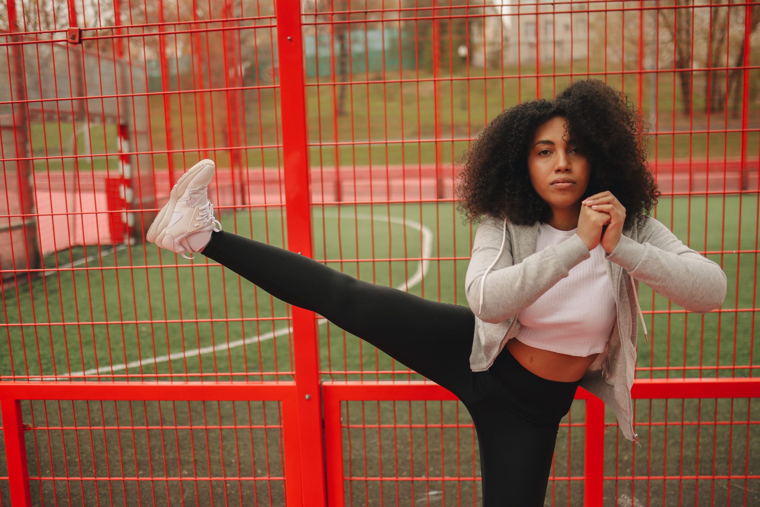 Femme s'étirant devant une clôture rouge