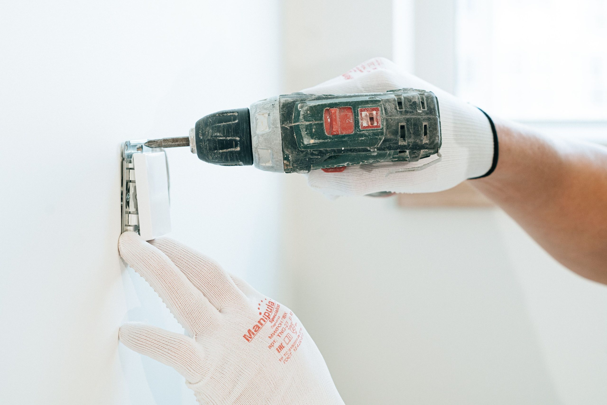 Mains gantées installant prise électrique mur
