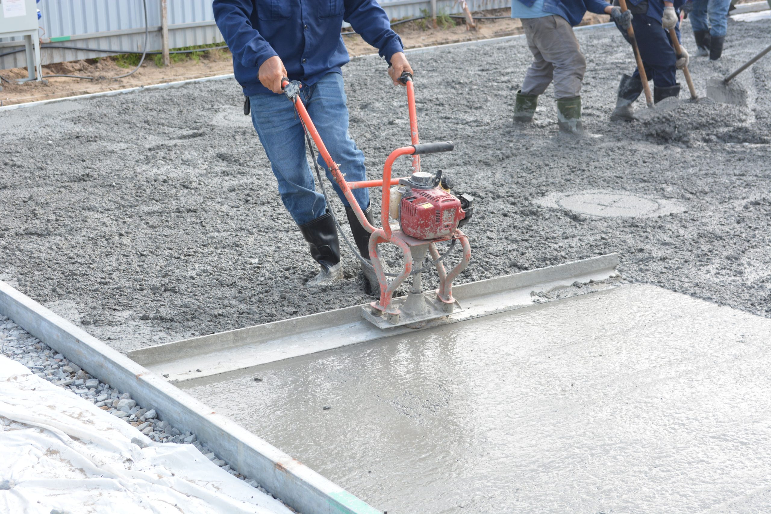 Équipe nivelant béton frais avec outils électriques