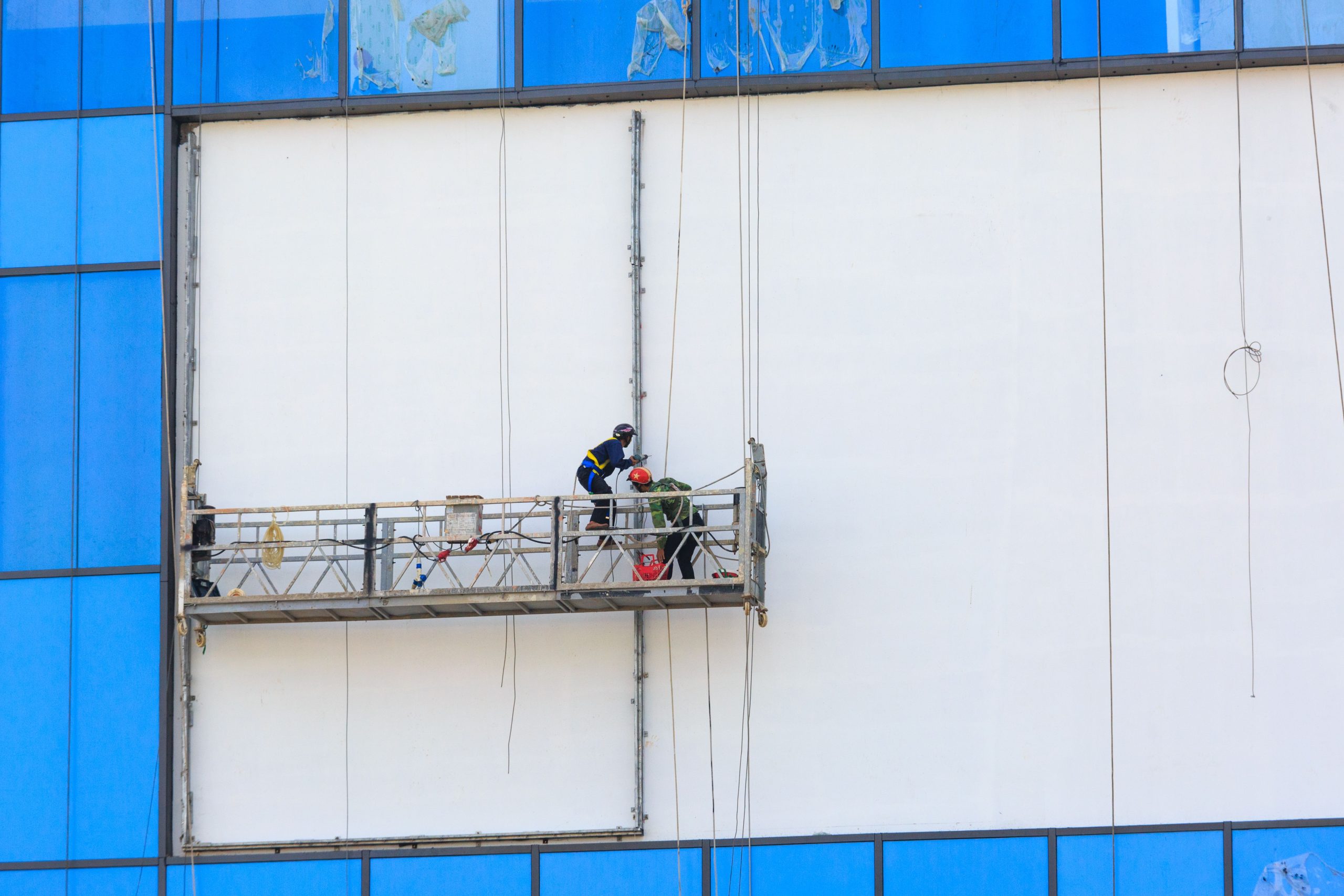 Deux ouvriers peignent et réparent façade bâtiment